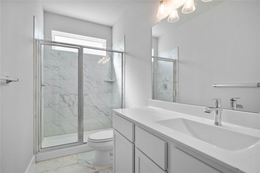 Secondary bathroom features light countertops and cabinets, neutral paint, shower/tub combo with tile surround, large mirror, tile floors, sleek fixtures and modern finishes.