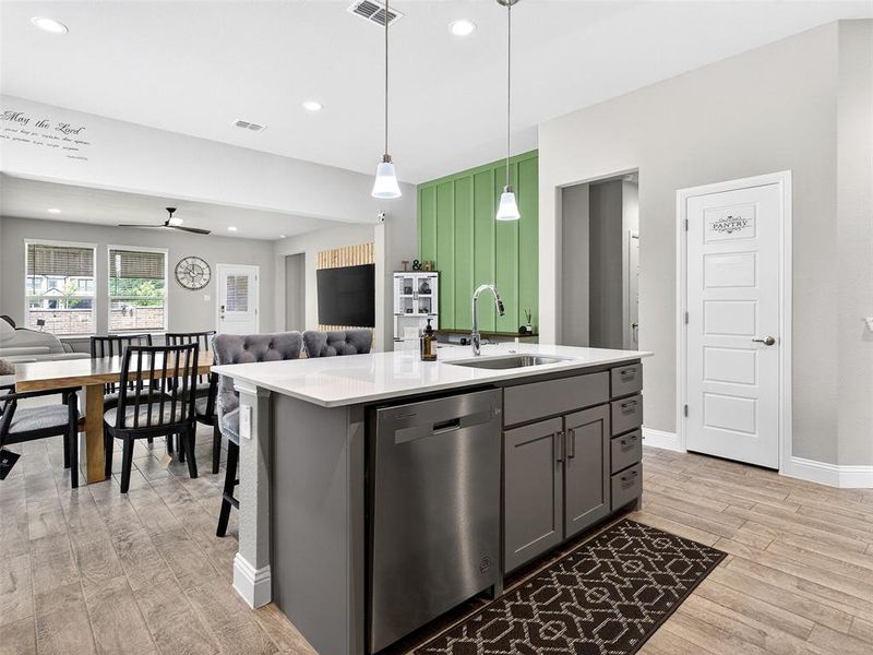 Modern kitchen island featuring a stainless steel sink with a high-arc faucet, integrated dishwasher, and under-counter cabinetry Modern kitchen island featuring a stainless steel sink with a high-arc faucet, integrated dishwasher, and under-counter cabinetry