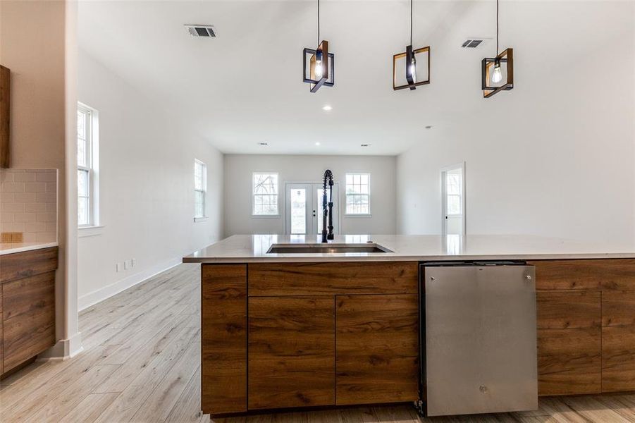 Kitchen with light wood-type flooring, a healthy amount of sunlight, brown cabinets, and a sink