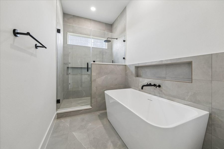 Freestanding soaking tub, oversized frameless shower, built in bench, and recessed storage niche combine beauty with functionality.