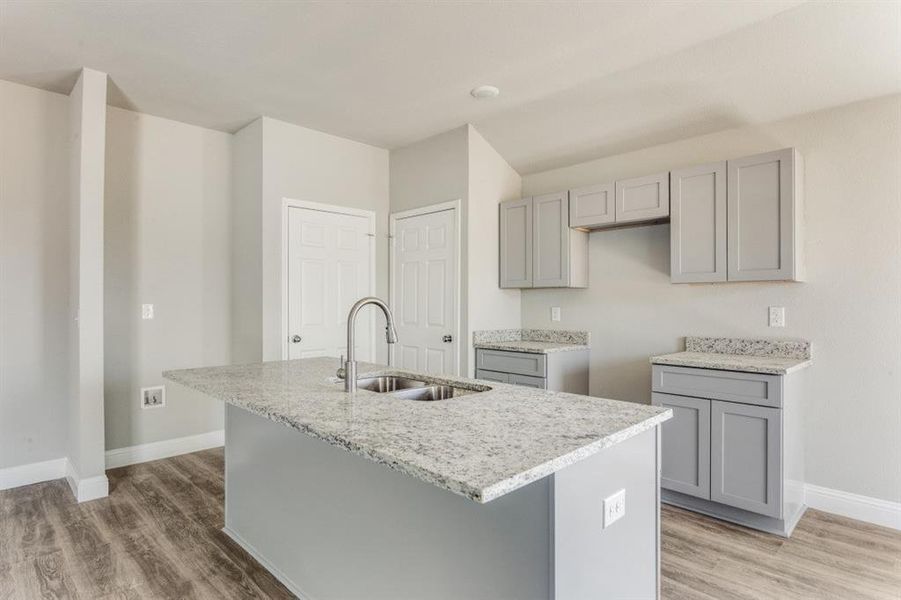 Kitchen featuring gray cabinets, light stone countertops, and light wood-type flooring