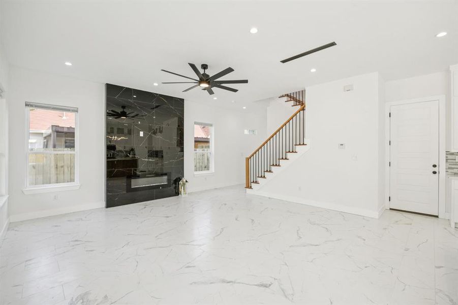 Unfurnished living room featuring stairway, light marble finish flooring, recessed lighting, and ceiling fan