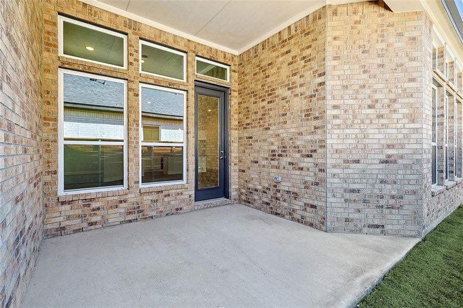 Property entrance with brick siding and a patio area