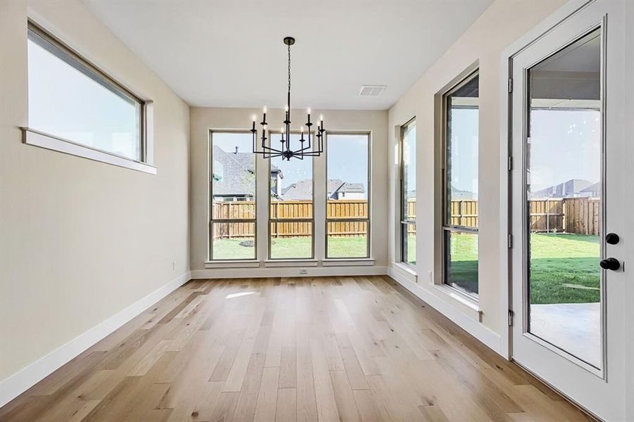 Unfurnished dining area featuring a chandelier and light wood-style floors Unfurnished dining area featuring a chandelier and light wood-style floors