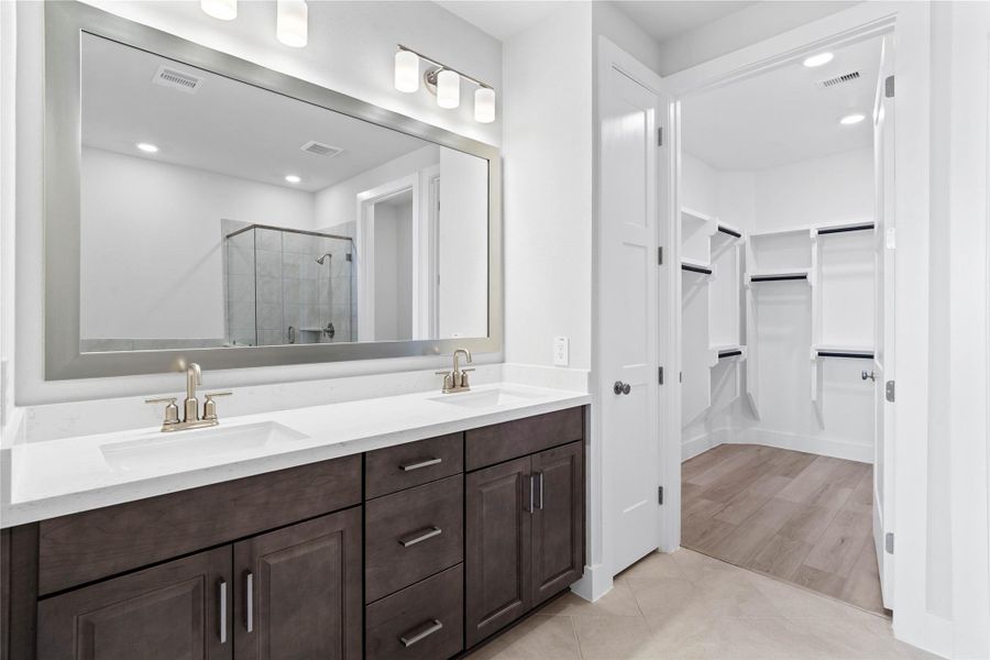 Retreat to a private, spa-like primary bathroom designed for relaxation and convenience. A generous double vanity with modern cabinetry offers ample space for two people. The connecting walk-in closet makes getting ready convenient. Retreat to a private, spa-like primary bathroom designed for relaxation and convenience. A generous double vanity with modern cabinetry offers ample space for two people. The connecting walk-in closet makes getting ready convenient.