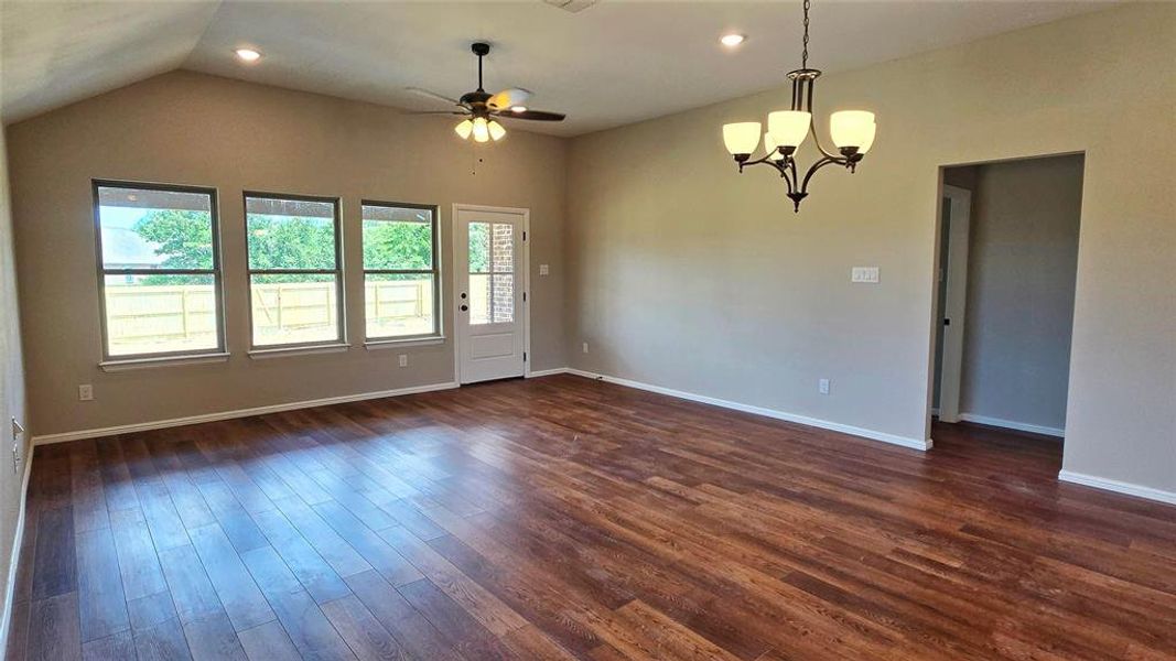 Spare room with dark wood-style floors, recessed lighting, a chandelier, a ceiling fan, and vaulted ceiling