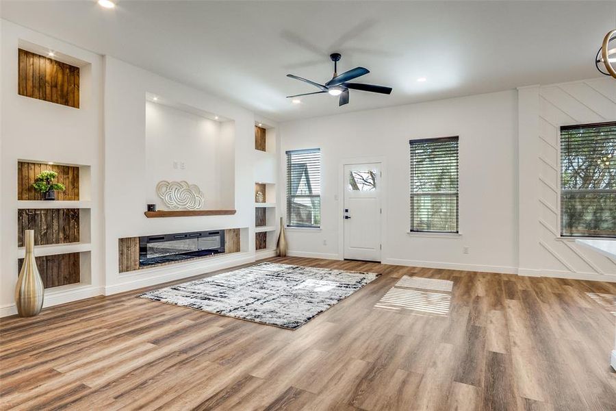 Foyer entrance featuring healthy amount of natural light, a ceiling fan, light wood-style flooring, a glass covered fireplace, and recessed lighting