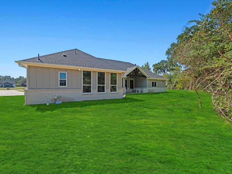 Back view of the home with plenty of green space. Back view of the home with plenty of green space.