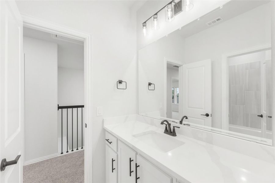 Bathroom with white vanity, quartz countertop, large mirror, and black hardware fixtures Bathroom with white vanity, quartz countertop, large mirror, and black hardware fixtures