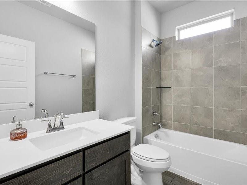 Full bathroom with hardwood / wood-style floors, vanity, toilet, and tiled shower / bath