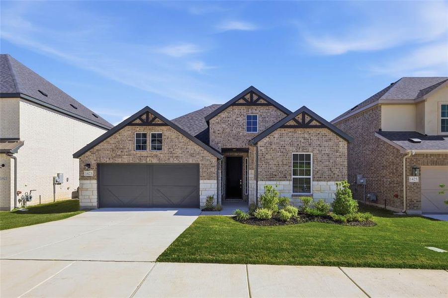 French country home featuring brick siding, a front lawn, concrete driveway, and a garage French country home featuring brick siding, a front lawn, concrete driveway, and a garage