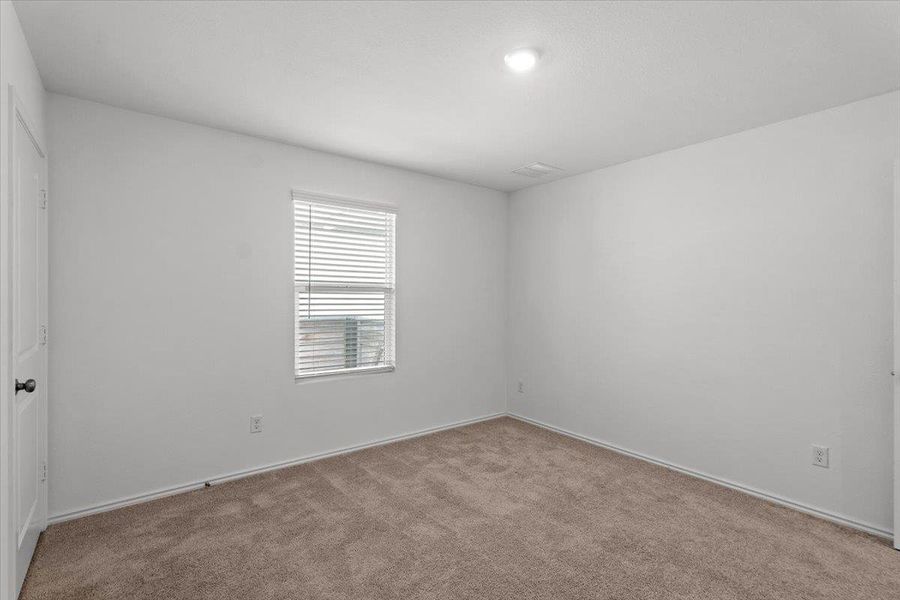A well-lit bedroom features plush carpeting and a window with blinds, offering a calm and private retreat. A well-lit bedroom features plush carpeting and a window with blinds, offering a calm and private retreat.