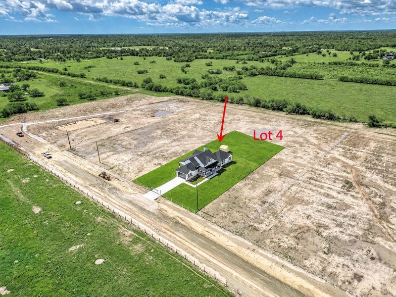 Aerial view highlighting the home’s location on Lot 4 and the surrounding open land within the subdivision.
