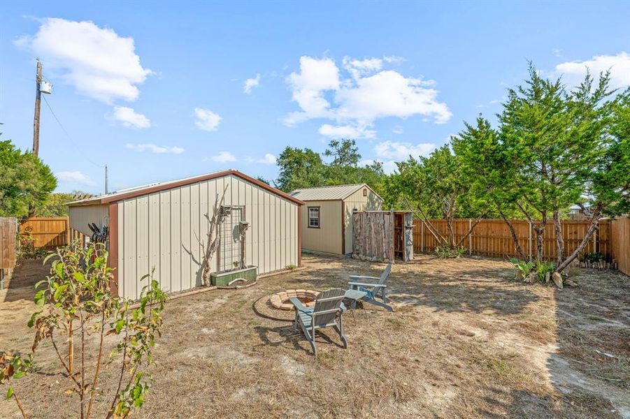 Fenced backyard featuring a fire pit and a shed