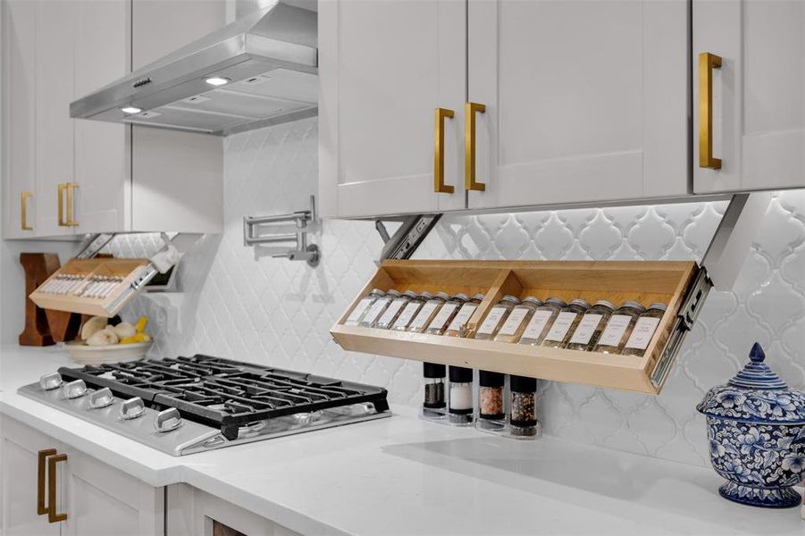 Interior details with white cabinets, backsplash, white gas stovetop, and range hood