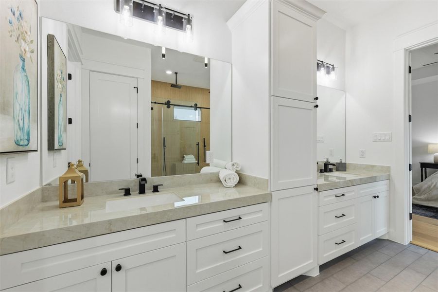 Dual vanities offer seamless daily flow, complemented by solid wood cabinetry and a dedicated linen cabinet that provides generous, well-organized storage.