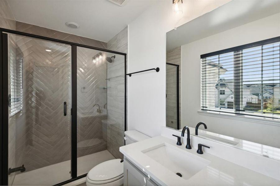 Bathroom featuring toilet, vanity, plenty of natural light, and a shower with door