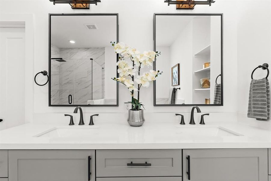 A sleek design with dual mirrors and separate sink over gray tone cabinets makes this ensuite timeless.