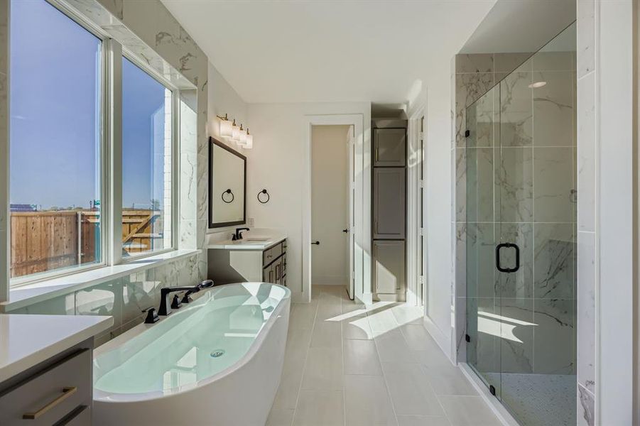 Full bath featuring vanity, a freestanding bath, a marble finish shower, and light tile patterned floors