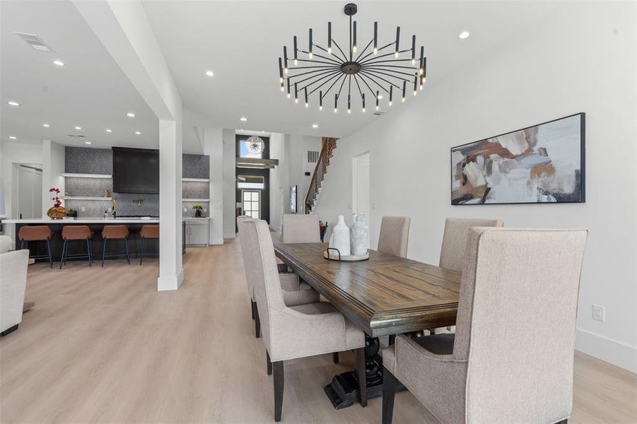 Dining space featuring a chandelier, light wood-style flooring, recessed lighting, and stairway