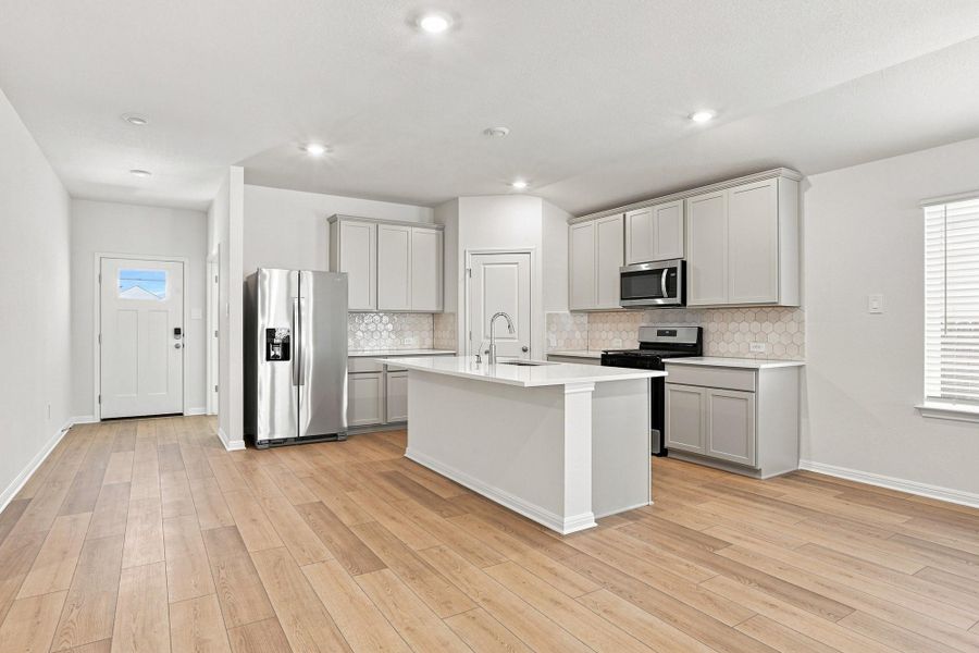 Gleaming wood flooring complements the modern kitchen cabinetry and spacious central prep island.