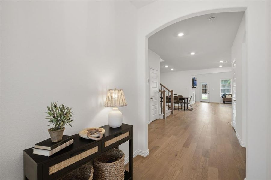 Welcoming entry with arched detail, wide hallway, and beautiful real wood flooring. The first impression feels bright, clean, and move-in ready.
