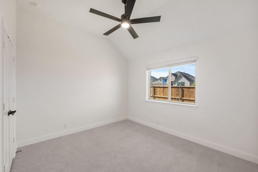 Empty bedroom with vaulted ceiling, ceiling fan, carpet flooring, and single window Empty bedroom with vaulted ceiling, ceiling fan, carpet flooring, and single window