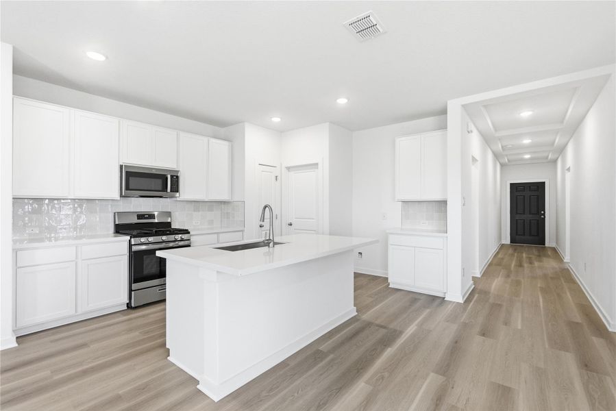 Kitchen with stainless steel appliances, white cabinetry, light wood-style floors, and recessed lighting