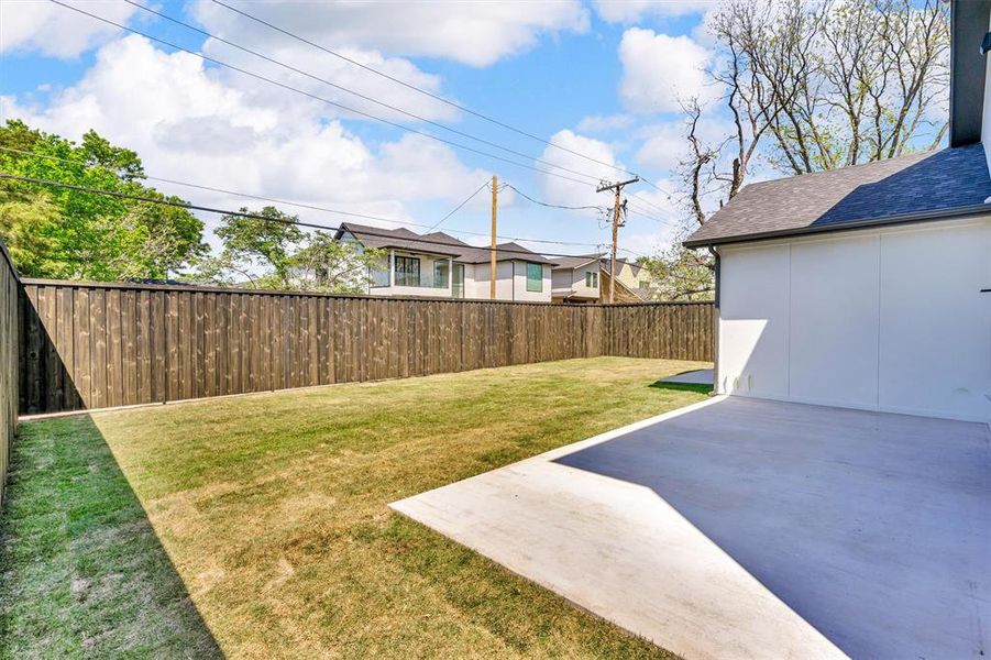 Rear view of property featuring a patio, roof with shingles, board and batten siding, fence, and a lawn
