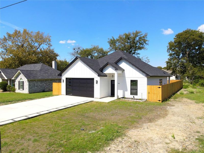 Modern farmhouse with board and batten siding, a shingled roof, driveway, and an attached garage Modern farmhouse with board and batten siding, a shingled roof, driveway, and an attached garage