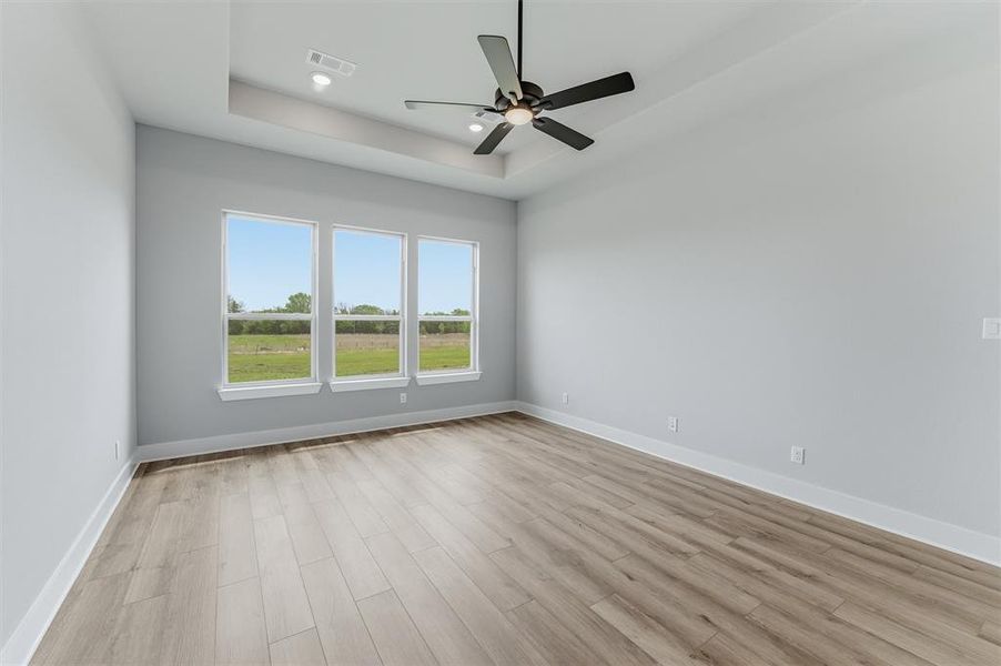 Spare room featuring ceiling fan, light wood-type flooring, a tray ceiling, and recessed lighting