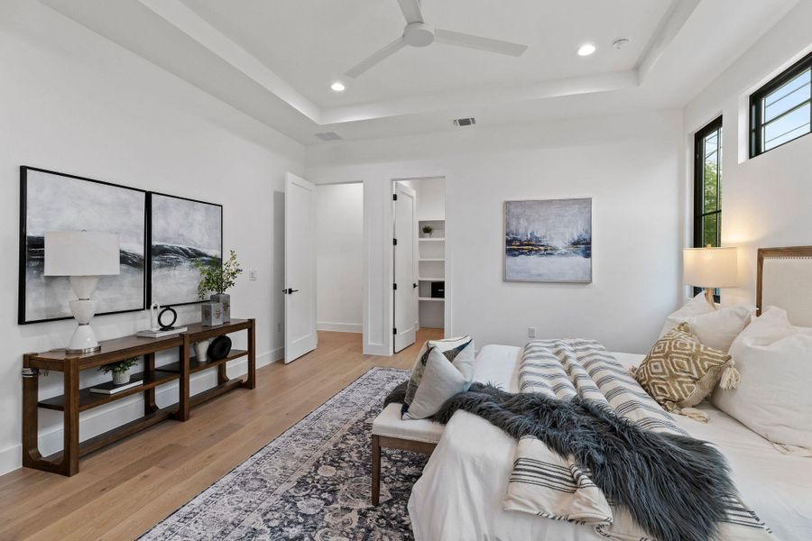 Bedroom with a tray ceiling, light wood-style floors, recessed lighting, a spacious closet, and a ceiling fan