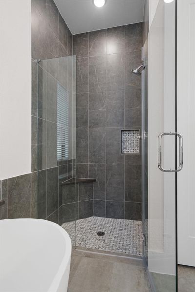 Full bath with a freestanding bath, a stall shower, tile patterned floors, tile walls, and recessed lighting Full bath with a freestanding bath, a stall shower, tile patterned floors, tile walls, and recessed lighting