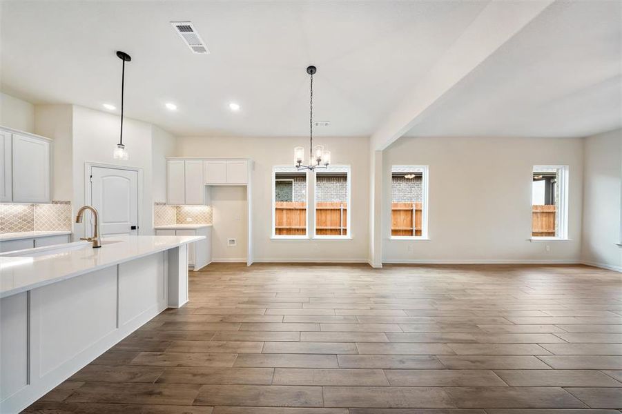 Kitchen featuring white cabinetry, a chandelier, backsplash, recessed lighting, and wood finished floors