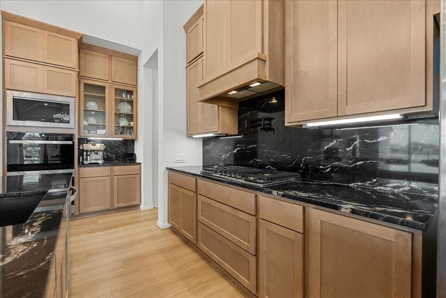 Chef’s kitchen overlooks the spacious living area and boasts double ovens, pot filler, granite countertops, designer backsplash, upgraded cabinetry, stainless steel appliances, stylish finishes, and oversized island seating.