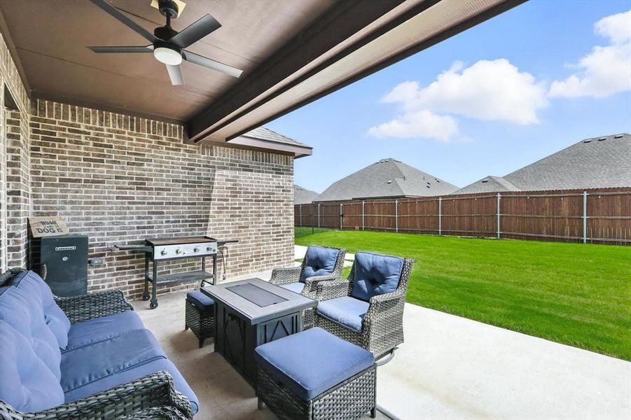 Fenced backyard with an outdoor hangout area, a ceiling fan, and a patio