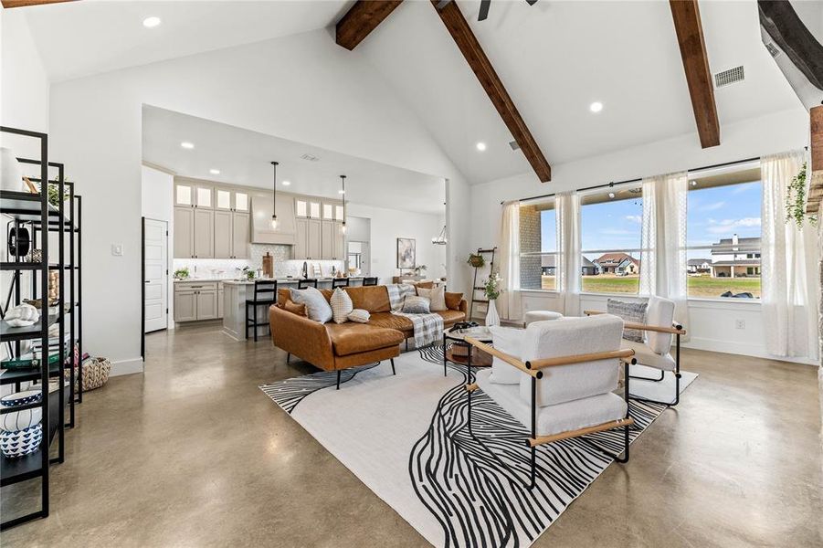 Living room with concrete flooring, high vaulted ceiling, beamed ceiling, and recessed lighting Living room with concrete flooring, high vaulted ceiling, beamed ceiling, and recessed lighting