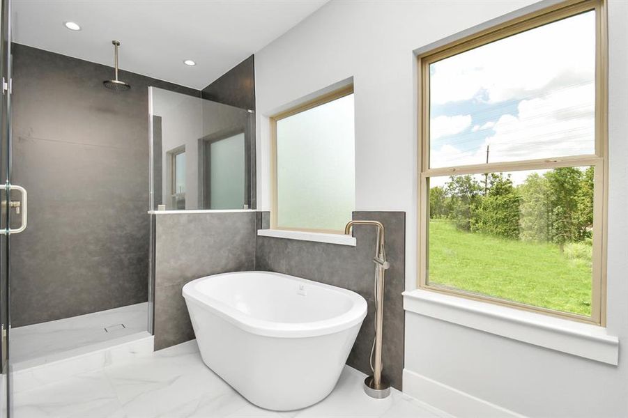 Here is another view of the primary ensuite bathroom which highlights the fabulous windows, the relaxing soaking tub and the spacious walk-in shower with a rainfall shower ahead above!