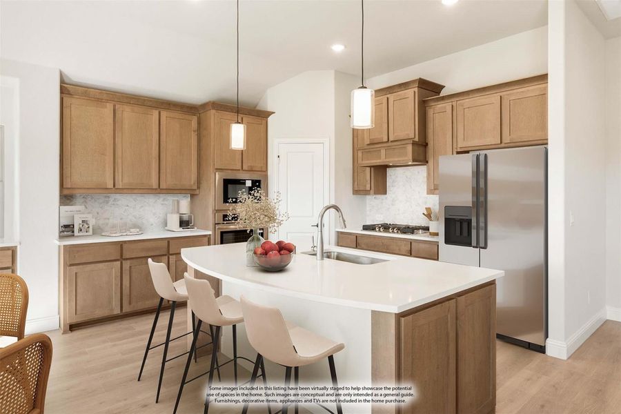Kitchen with light wood cabinets, white island with seating, pendant lights, and stainless steel appliances