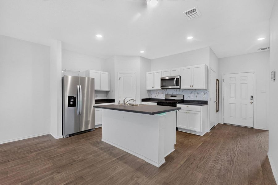 Rich wood flooring anchors this open kitchen layout featuring a central island and recessed lighting. Rich wood flooring anchors this open kitchen layout featuring a central island and recessed lighting.