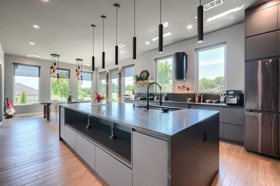 Kitchen featuring modern cabinets, a spacious island, stainless steel refrigerator, pendant lighting, and recessed lighting Kitchen featuring modern cabinets, a spacious island, stainless steel refrigerator, pendant lighting, and recessed lighting