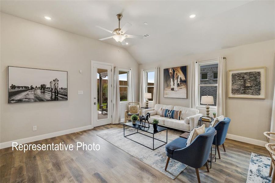 Living room featuring ceiling fan, hardwood / wood-style floors, and vaulted ceiling