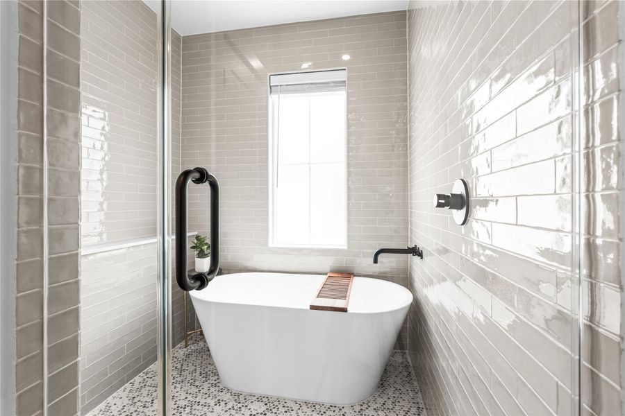 The wet room pairs a freestanding soaking tub with a walk-in shower, wall-mounted fixtures, and floor-to-ceiling tile.