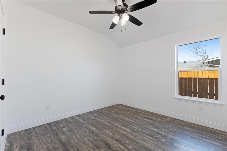 Unfurnished room with vaulted ceiling, dark wood finished floors, a ceiling fan, and baseboards