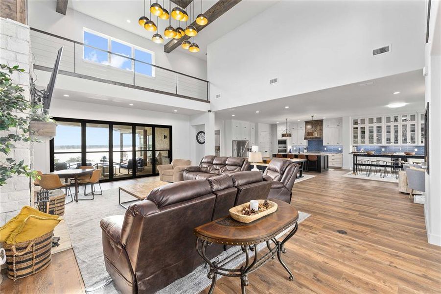 Living area featuring light wood-type flooring, a chandelier, a water view, recessed lighting, and a high ceiling