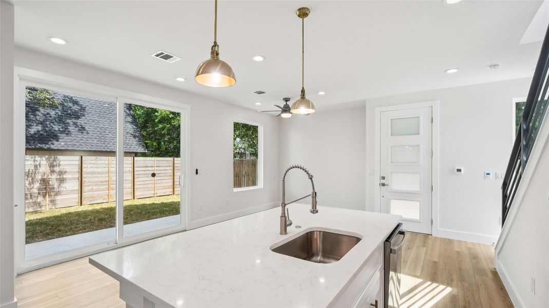 Kitchen with light wood-type flooring, light stone counters, hanging light fixtures, plenty of natural light, and recessed lighting Kitchen with light wood-type flooring, light stone counters, hanging light fixtures, plenty of natural light, and recessed lighting