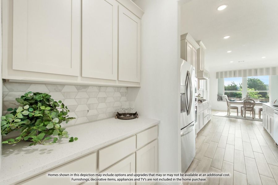 Kitchen with white cabinets, geometric tile backsplash, quartz counters, and stainless refrigerator opening to dining area Kitchen with white cabinets, geometric tile backsplash, quartz counters, and stainless refrigerator opening to dining area