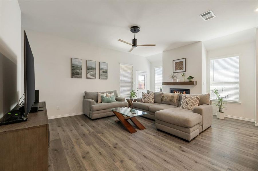 Living room featuring light wood finished floors, a glass covered fireplace, and ceiling fan Living room featuring light wood finished floors, a glass covered fireplace, and ceiling fan