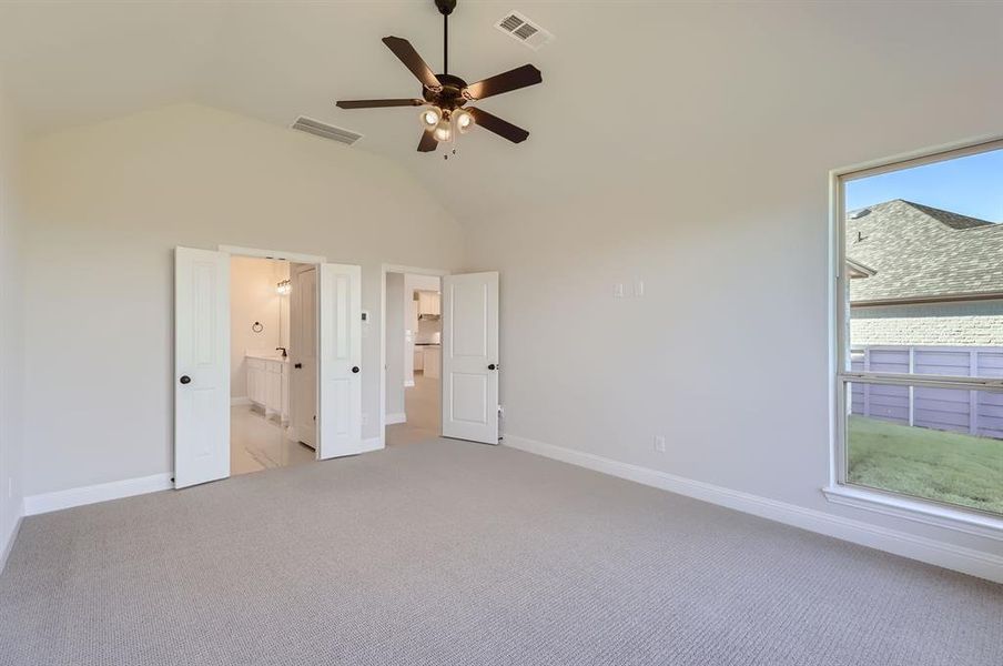 Unfurnished bedroom featuring light carpet, connected bathroom, and ceiling fan