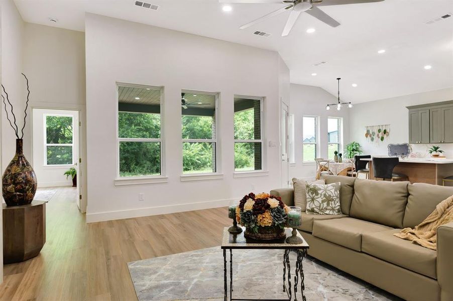 Spacious living area featuring wood-finish flooring, high vaulted ceilings, and recessed lighting Spacious living area featuring wood-finish flooring, high vaulted ceilings, and recessed lighting